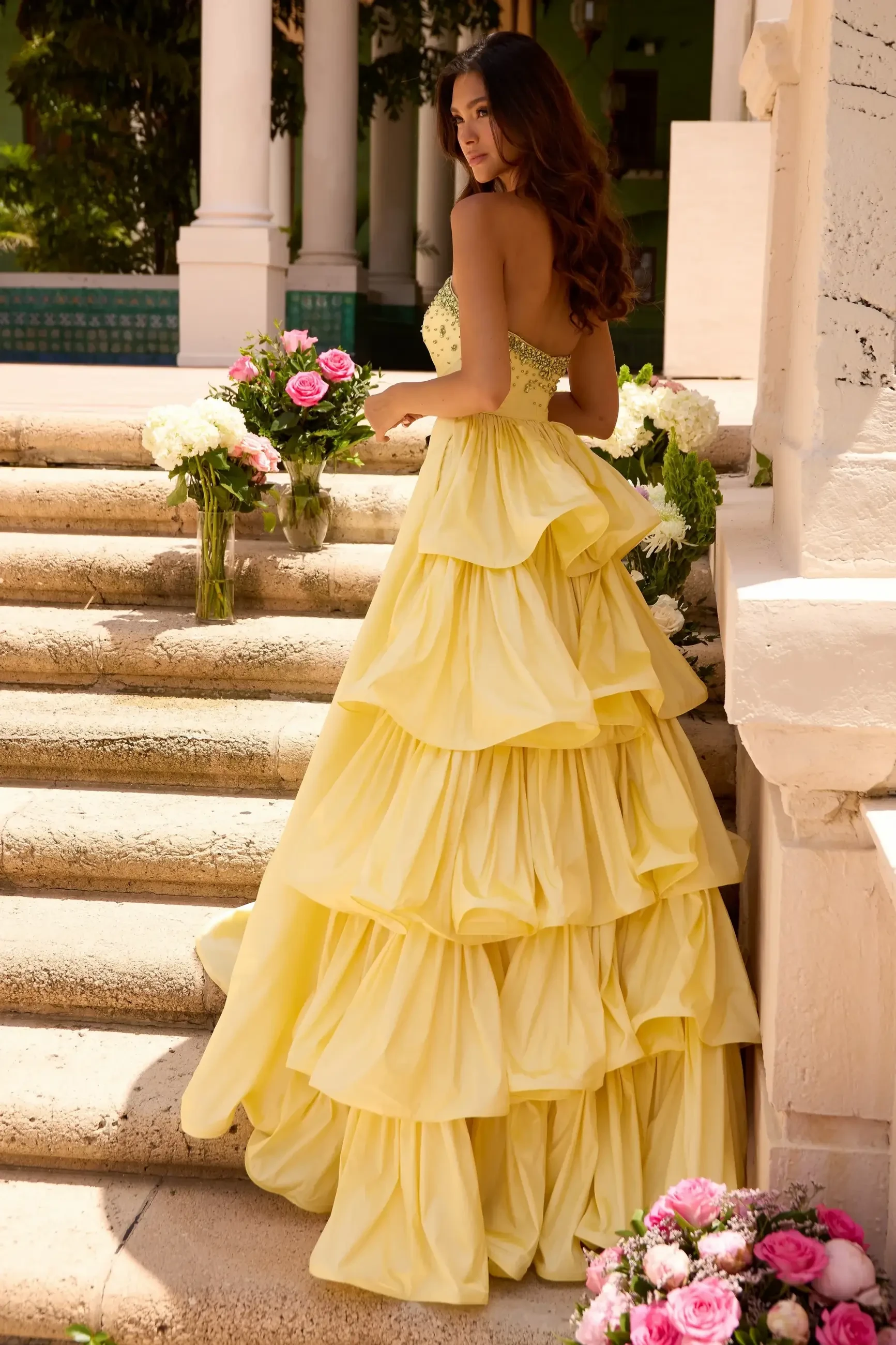 model is wearing a tiered ruffled yellow prom dress