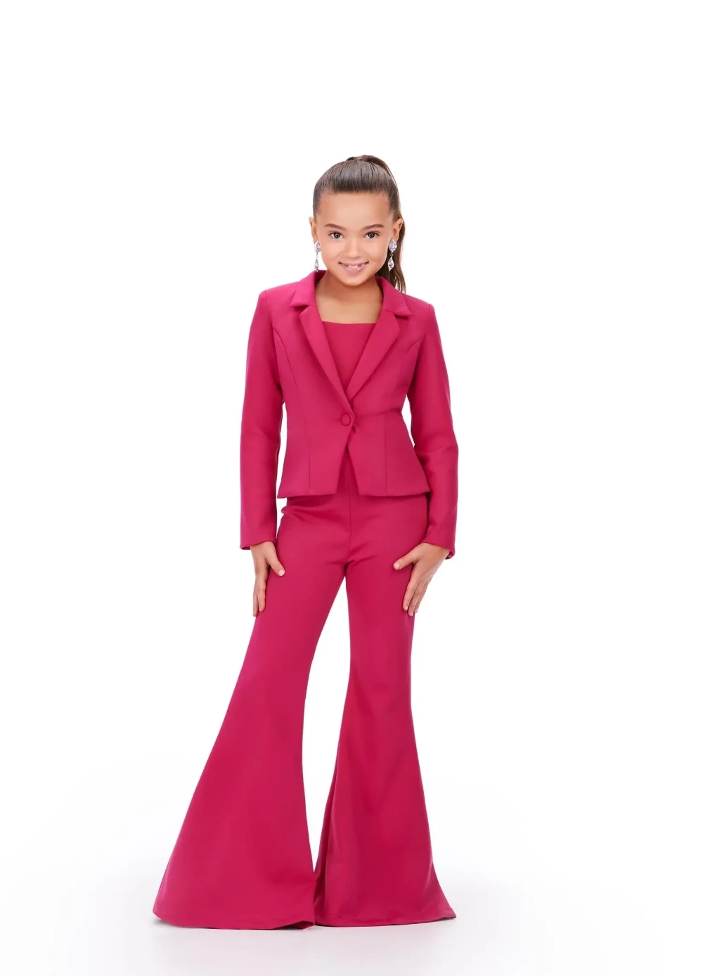 A young girl wearing a vibrant pink pageant interview pantsuit with a fitted blazer and dramatic flared pants, posing confidently against a white background.